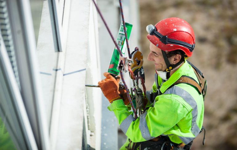 Técnico electricista realizando mantenimiento en estructura industrial con equipo de seguridad